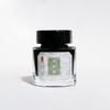 Cathay Verdant Courtyard fountain pen ink bottle with vibrant green ink, detailed label and ink cap in natural lighting.
