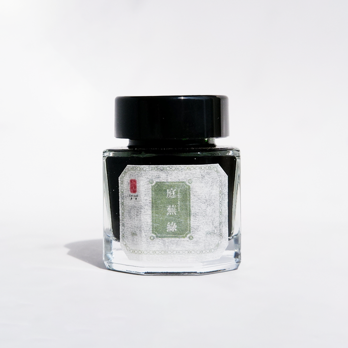 Cathay Verdant Courtyard fountain pen ink bottle with vibrant green ink, detailed label and ink cap in natural lighting.