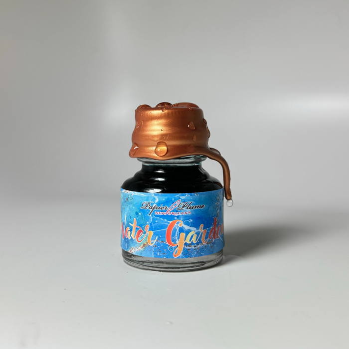 Papier Plume limited edition fountain pen ink bottle labeled Water Gardens, with colorful ink swirls and elegant packaging.