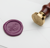 Wax seal featuring an elegant script monogram design from Papier Plume, with a smooth, circular seal and intricate script details.