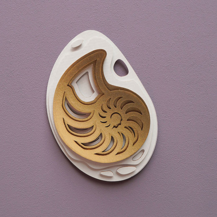 Gold paper fossil art of an ammonite shell by Assembli, showcasing intricate fossil details and artistic design.