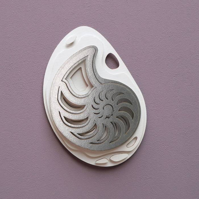 Silver paper fossil art depicting a detailed ammonite fossil, created by Assembli.