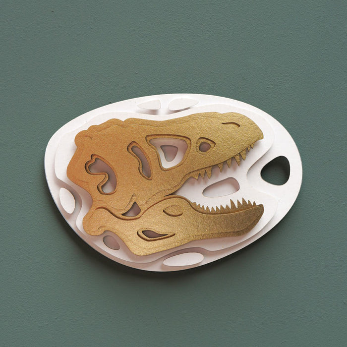 Gold paper fossil art of a Tyrannosaurus rex craft by Assembli, showcasing detailed T-Rex fossil design on a white background.