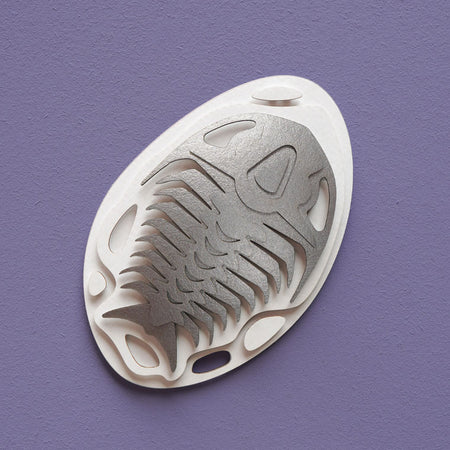 Silver paper fossil art of a trilobite by Assembli, detailed and textured trilobite fossil sculpture on a white background.