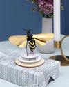 Gold paper wasp craft made by Assembli, showcasing a detailed and artistic paper wasp sculpture with intricate design.