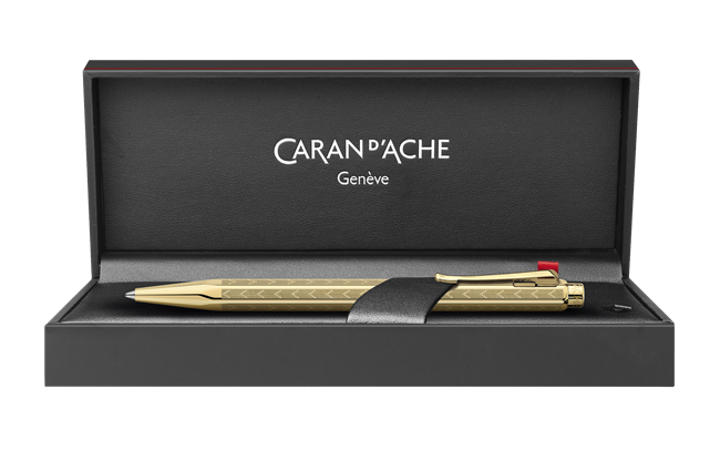 Caran D'Ache Gilded Ecridor Chevron ballpoint pen with gold accents and detailed chevron pattern, close-up view