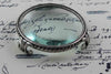 Large Le Potier D'etain magnifying glass on feet, circular design, with a clear glass lens for detailed viewing.