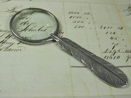 Small Le Potier D'etain magnifying glass with a feather handle, handheld magnifier for detailed viewing.