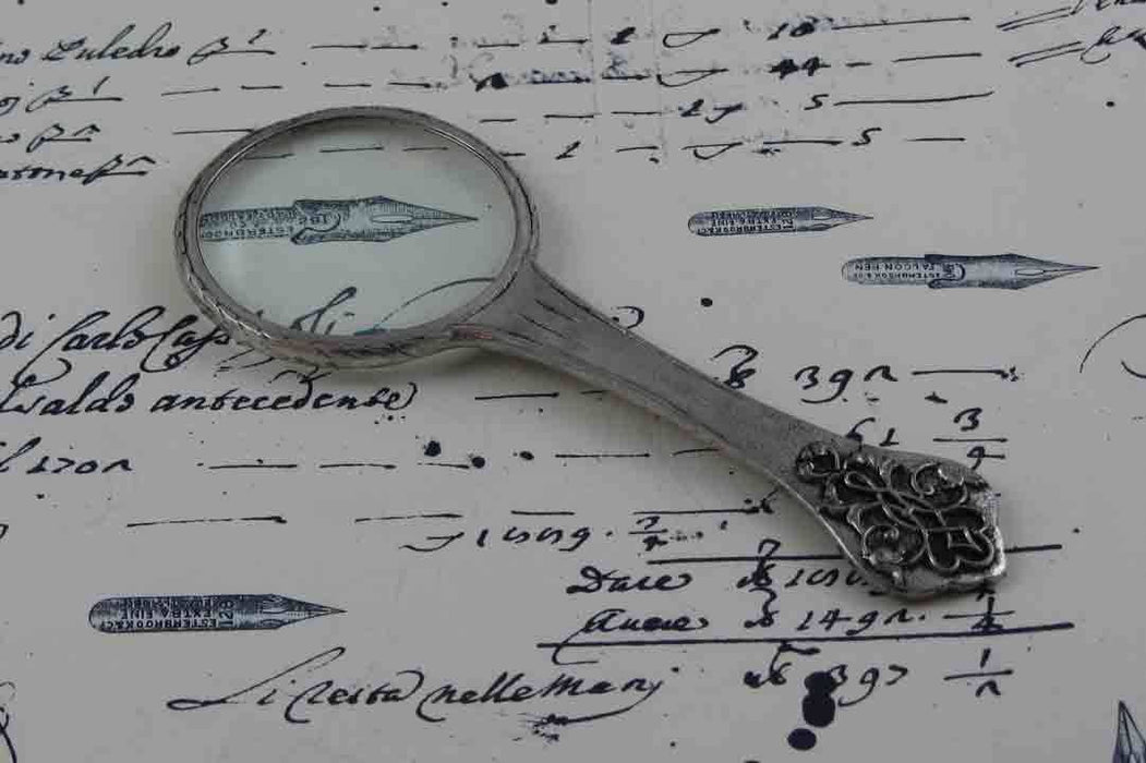 Small Le Potier D'etain magnifying glass with handle and intricate filigree design, ideal for detailed viewing and display.