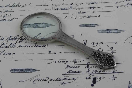 Small Le Potier D'etain magnifying glass with handle and intricate filigree design, ideal for detailed viewing and display.