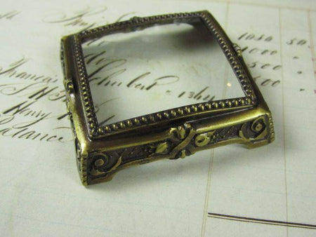 Small Le Potier D'etain pewter magnifying glass on square feet, decorative and functional magnifier for close-up viewing.