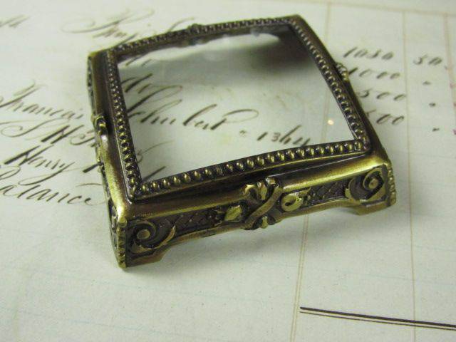 Small Le Potier D'etain pewter magnifying glass on square feet, decorative and functional magnifier for close-up viewing.