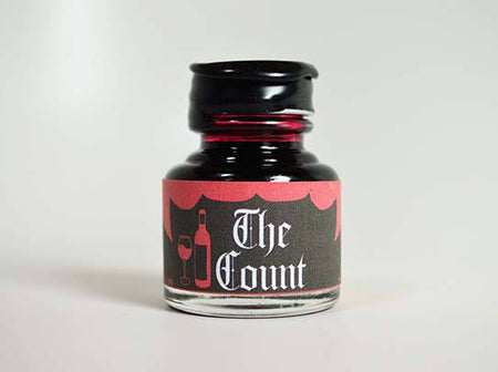 Bottled ink labeled "The Count" by Papier Plume, showcasing deep, rich fountain pen ink in a clear glass bottle.