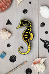 Crafts paper seahorse by Assembli made from Caribbean green metallic paper, showcasing detailed, colorful origami-style sea creature.