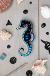Assembli Paper Seahorse craft made from Caribbean green metallic paper with intricate details and textured fins.