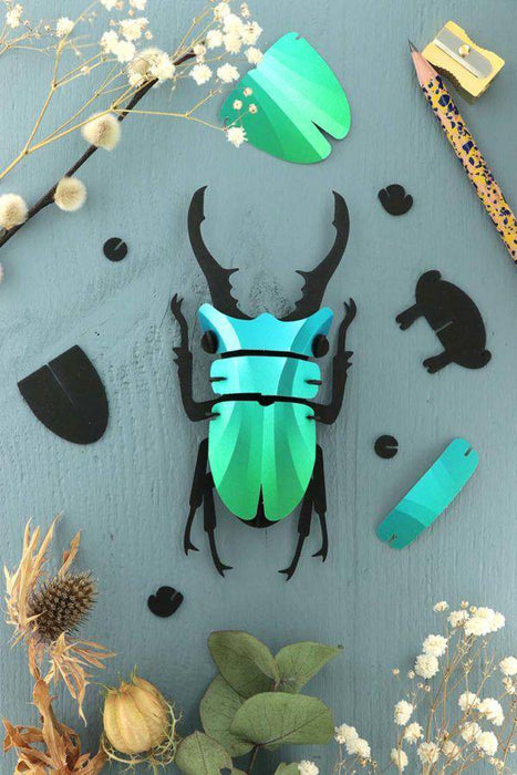 Small paper stag beetle craft made of green metal paper by Assembli, featuring detailed insect design for creative projects.