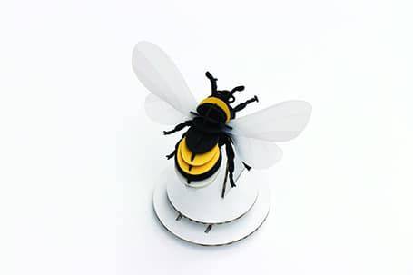 Craft paper Bumble Bee by Assembli, featuring yellow and black paper wings and body for DIY craft projects.