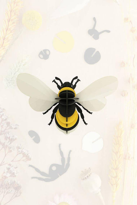 Colorful paper bumble bee craft by Assembli featuring yellow and black paper with detailed wings and antennae.