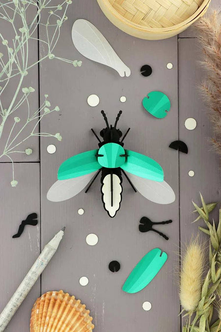 Emerald green metallic Paper Firefly craft by Assembli, made from shimmering paper with detailed wings and body.