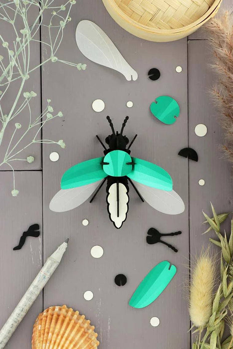 Emerald green metallic Paper Firefly craft by Assembli, made from shimmering paper with detailed wings and body.