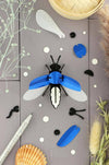 Emerald green metallic paper firefly craft by Assembli made from colorful, shiny paper for creative arts and crafts projects.