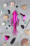 Pink paper craft squid made by Assembli, featuring detailed paper fins and a whimsical design for creative craft projects.