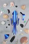 Pink paper craft squid made by Assembli, featuring detailed paper folds and a playful design for creative crafts.