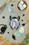 Colorful rainbow paper scarab beetle craft made from folded paper by Assembli, showcasing vibrant, detailed origami insect art.