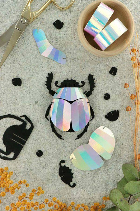 Colorful rainbow paper scarab beetle craft made from folded paper by Assembli, showcasing vibrant, detailed origami insect art.