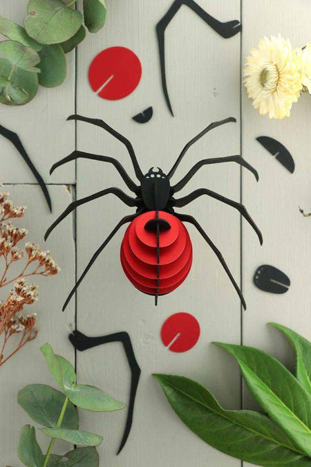 Red paper spider craft made from Assembli Paper Spider kit, showcasing detailed paper legs and body for creative arts projects.
