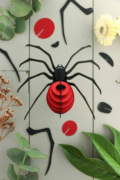 Red paper spider craft made from Assembli Paper Spider kit, showcasing detailed paper legs and body for creative arts projects.