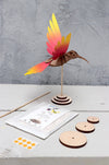 Yellow and blue paper craft of a colibri bird made by Assembli, showcasing colorful, artistic paper craft materials.