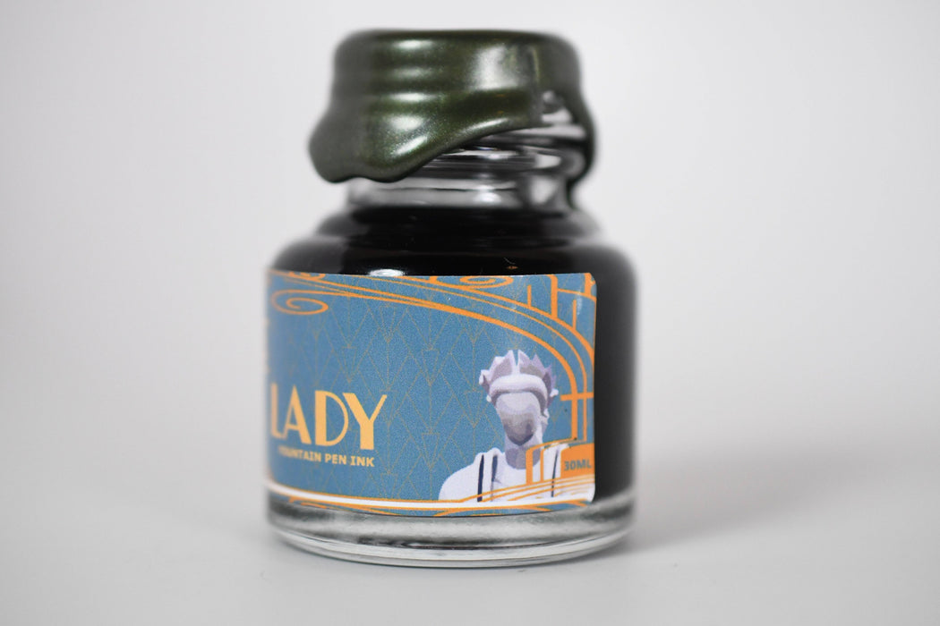 Papier Plume Chicago Pen Show Faceless Lady Shimmer Fountain Pen Ink bottle with label and shimmering ink in a glass container.