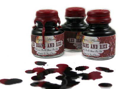 Papier Plume New Orleans Collection fountain pen ink in a red beans and rice color, shown in a glass bottle with ink swatch.