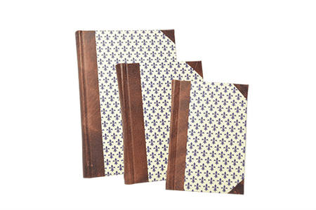 Handcrafted leather-trimmed journal with fleur de lys design and modern spine by Il Cartiglio, featuring lined pages and elegant craftsmanship.