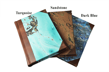 Handcrafted Il Cartiglio leather-trimmed journal with marbled paper and modern spine, featuring lined pages and turquoise cover.