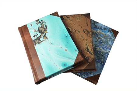 Small handcrafted leather journal by Il Cartiglio with dark green leather trim, lined pages, marbled paper, and an old-world spine design.